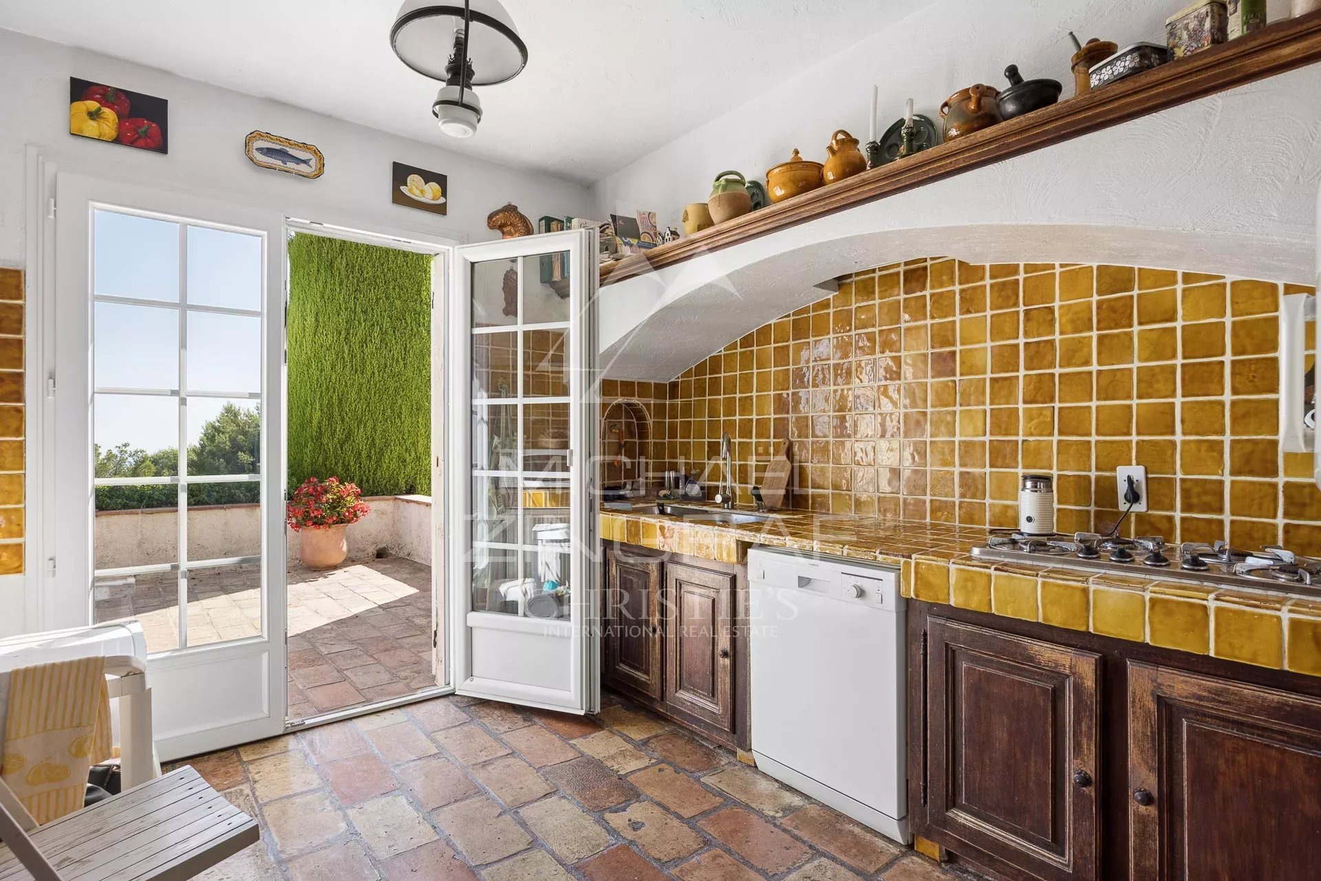 Villa kitchen in Saint-Paul-de-Vence Bright kitchen with terracotta tiles and wooden furniture, opening onto an outdoor space.