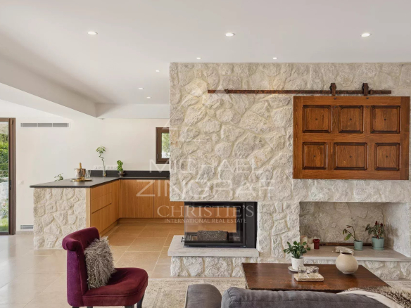 Intérieur d'une villa moderne avec cheminée en pierre et cuisine ouverte à Saint-Paul-de-Vence.
