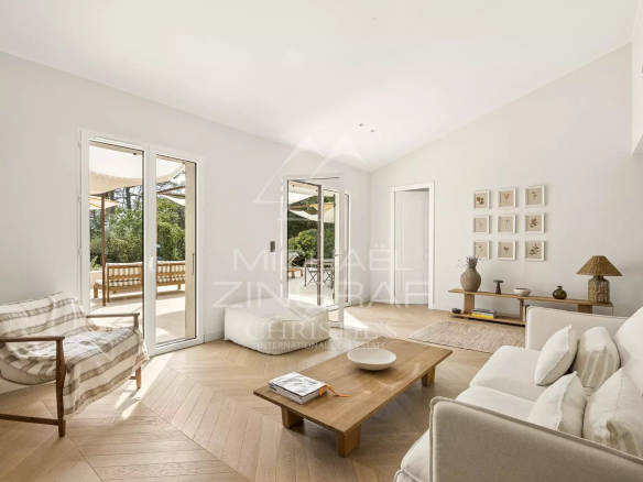 Intérieur d'une villa rénovée avec un salon lumineux et moderne, vue sur le parc extérieur.