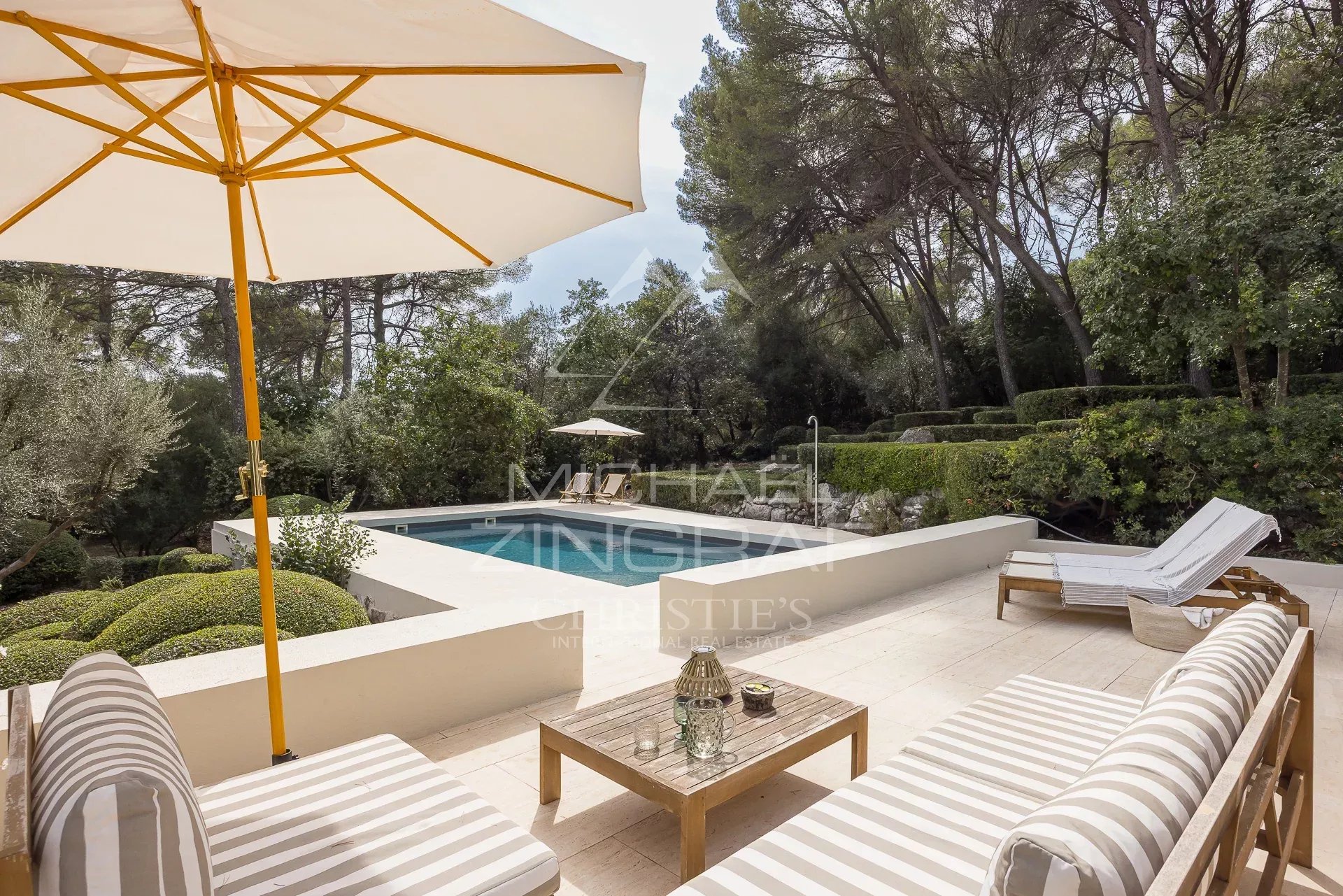Terrasse de villa avec piscine Terrasse d'une villa rénovée avec piscine, chaises longues et parasol, entourée de verdure.