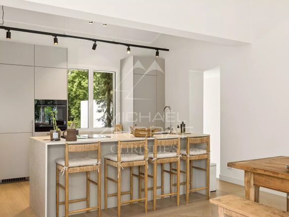 Cuisine moderne avec bar et chaises dans une villa rénovée.