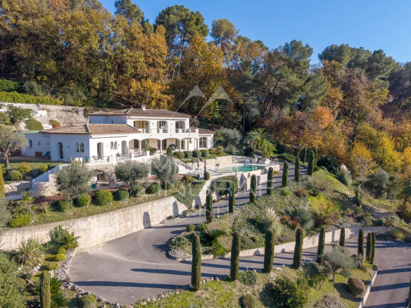 Modern villa with views of Saint-Paul de Vence, surrounded by greenery and trees.