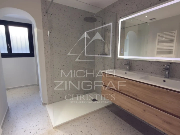 Salle de bain moderne avec douche et meuble en bois, murs en pierre, dans une propriété à Tourrettes-sur-Loup.