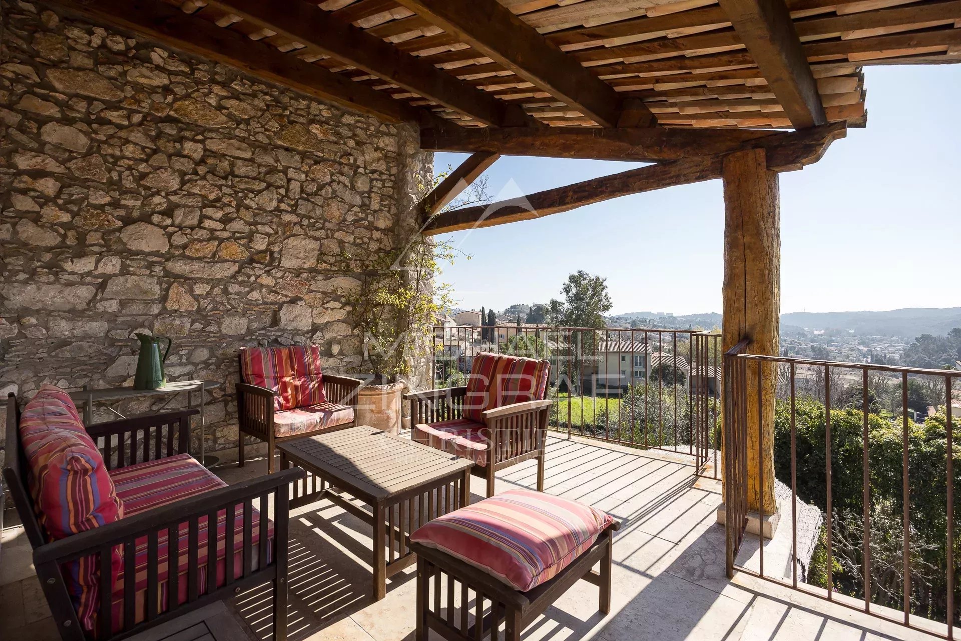 Terrasse ensoleillée à La Colle-sur-Loup Terrasse ensoleillée avec mobilier en bois et vue sur le village de La Colle-sur-Loup.