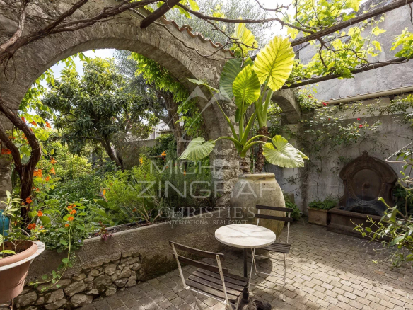 Jardin avec arches en pierre et plantes luxuriantes à La Colle-sur-Loup.