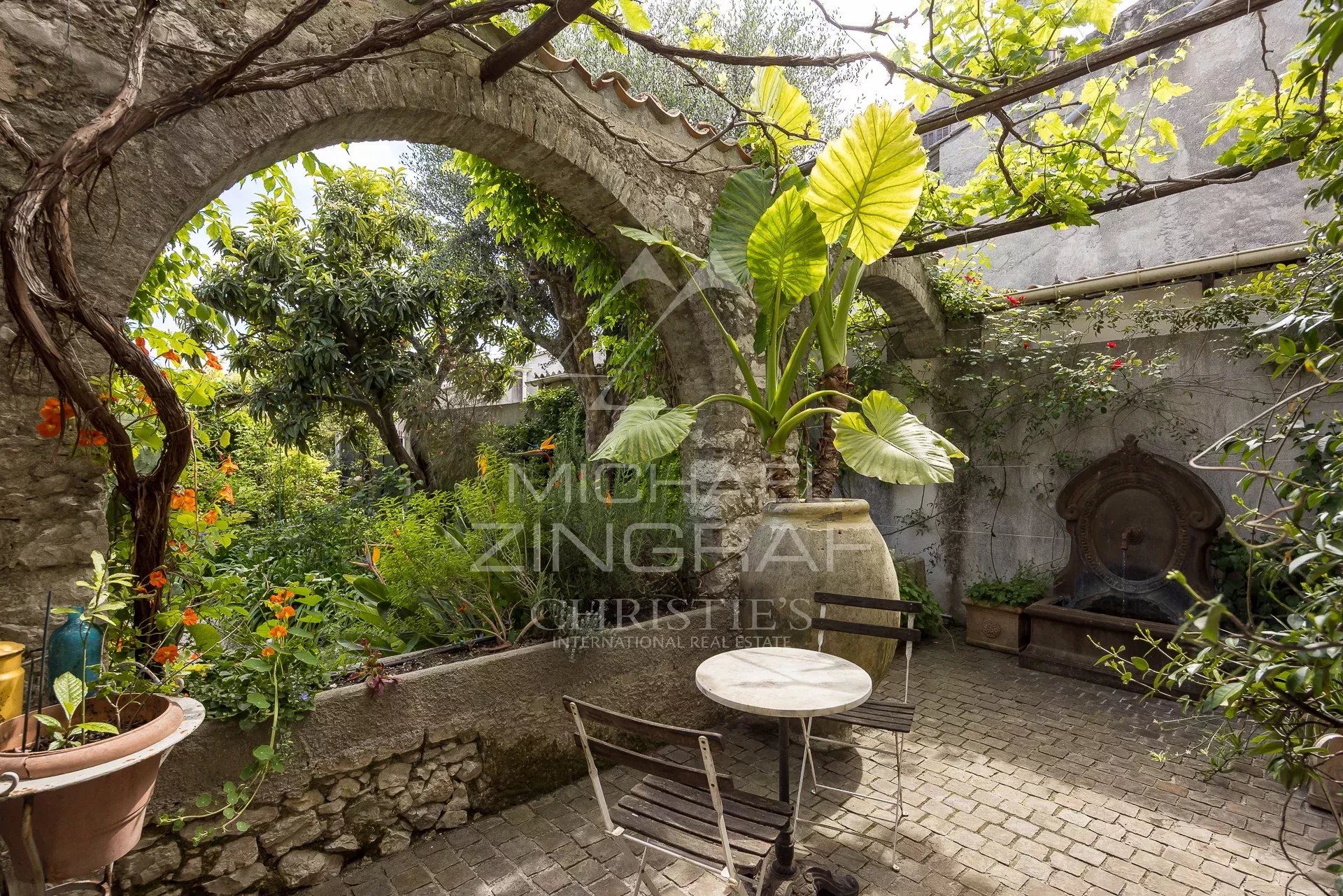 Jardin au cœur de La Colle-sur-Loup Jardin avec arches en pierre et plantes luxuriantes à La Colle-sur-Loup.