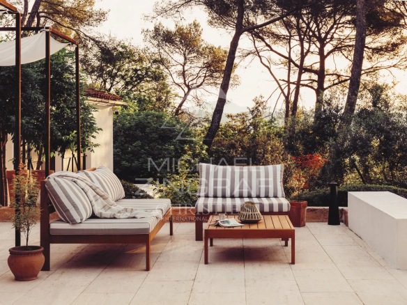 Terrace of a renovated property with garden furniture and view of a landscaped park in La Colle-sur-Loup.
