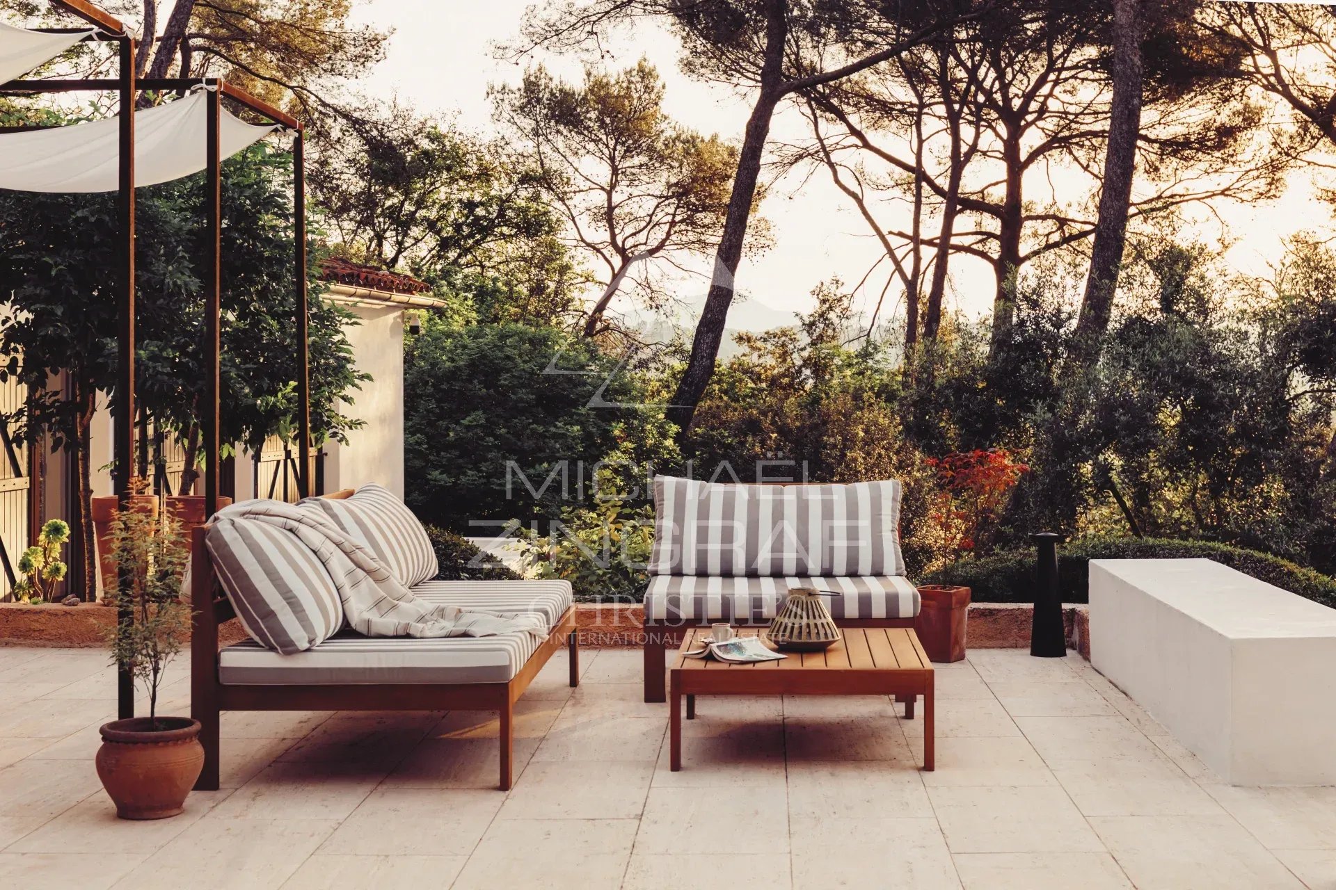 Terrace of a renovated villa in La Colle-sur-Loup Terrace of a renovated property with garden furniture and view of a landscaped park in La Colle-sur-Loup.