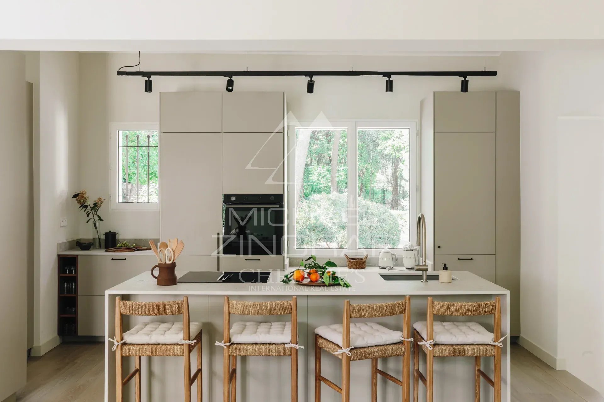 Renovated kitchen in a villa in La Colle-sur-Loup Modern kitchen with central island and bar, overlooking a landscaped park.