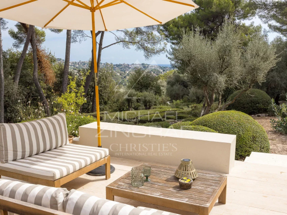 Terrace of a renovated villa with furniture, overlooking a landscaped park in La Colle-sur-Loup.