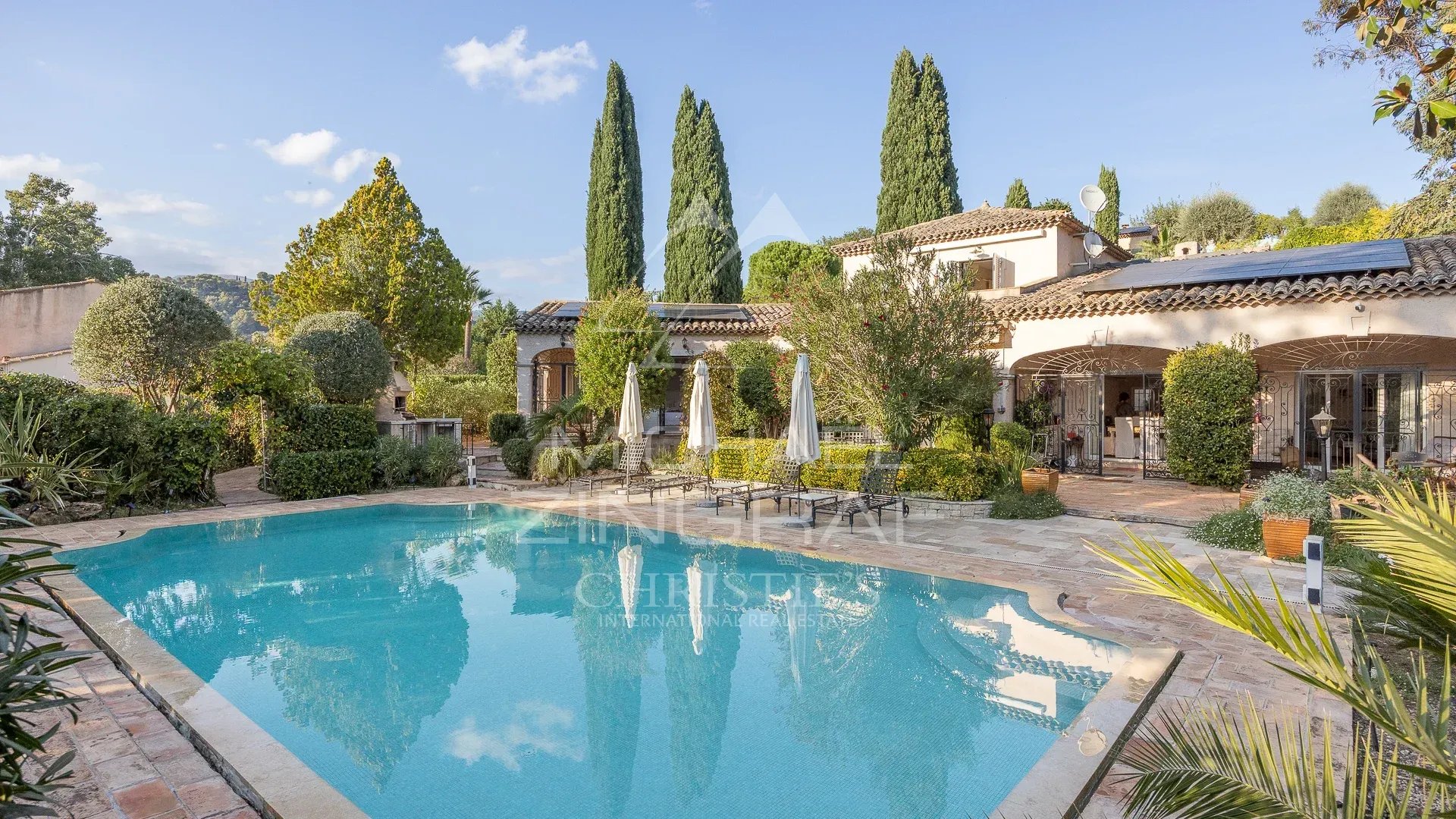 Propriété avec piscine et jardins à Saint-Paul-de-Vence, entourée d'arbres et de terrasses.