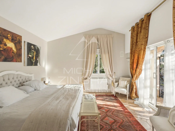 Chambre lumineuse avec lit king size, tapis et rideaux dorés dans une propriété à Saint-Paul-de-Vence.