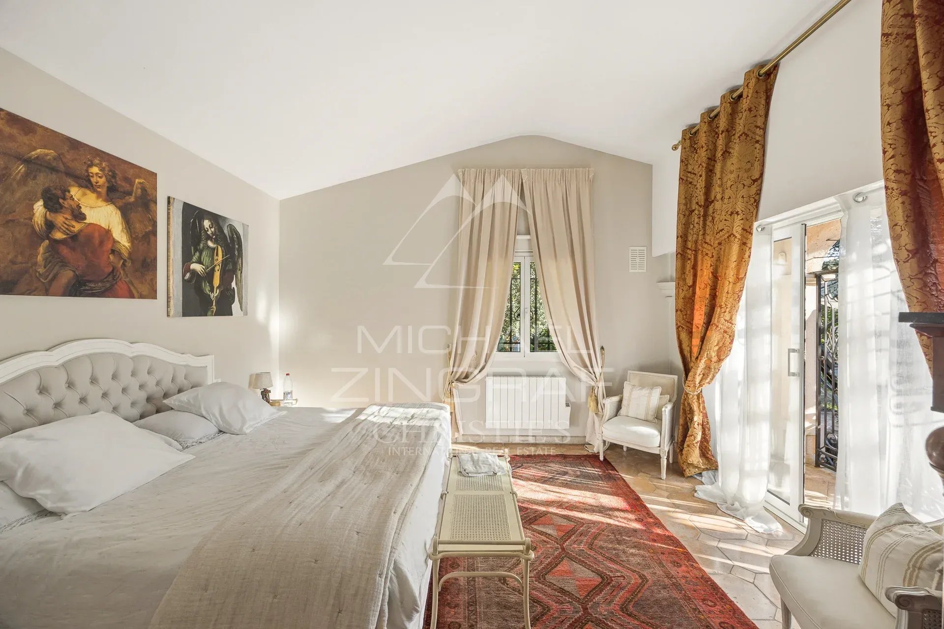 Chambre lumineuse avec lit king size, tapis et rideaux dorés dans une propriété à Saint-Paul-de-Vence.