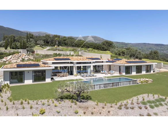 Modern single-story villa with orange-tiled roof, solar panels, and a rectangular pool in a landscaped countryside setting.