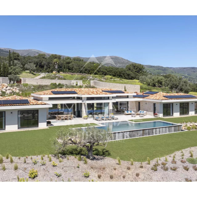 Modern single-story villa with orange-tiled roof, solar panels, and a rectangular pool in a landscaped countryside setting.