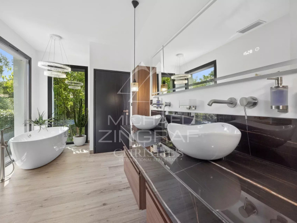 Salle de bain moderne avec baignoire et lavabo, lumière naturelle à travers les fenêtres.