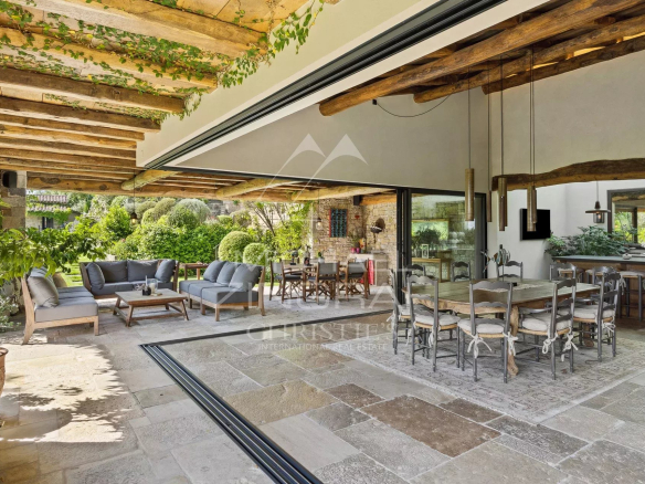 Terrasse d'une villa en Provence avec mobilier extérieur et vue sur un jardin verdoyant.