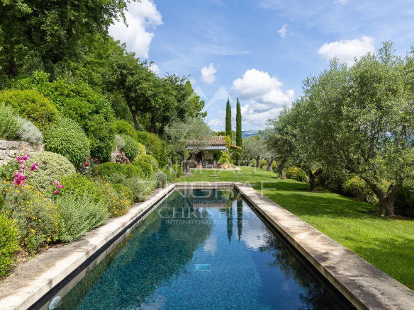 Vue d'une villa de plain-pied avec piscine et jardin en Provence, entourée d'arbres et de fleurs.