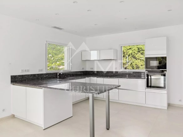 Cuisine moderne et lumineuse d'une villa contemporaine, avec des meubles blancs et un plan de travail en granit.