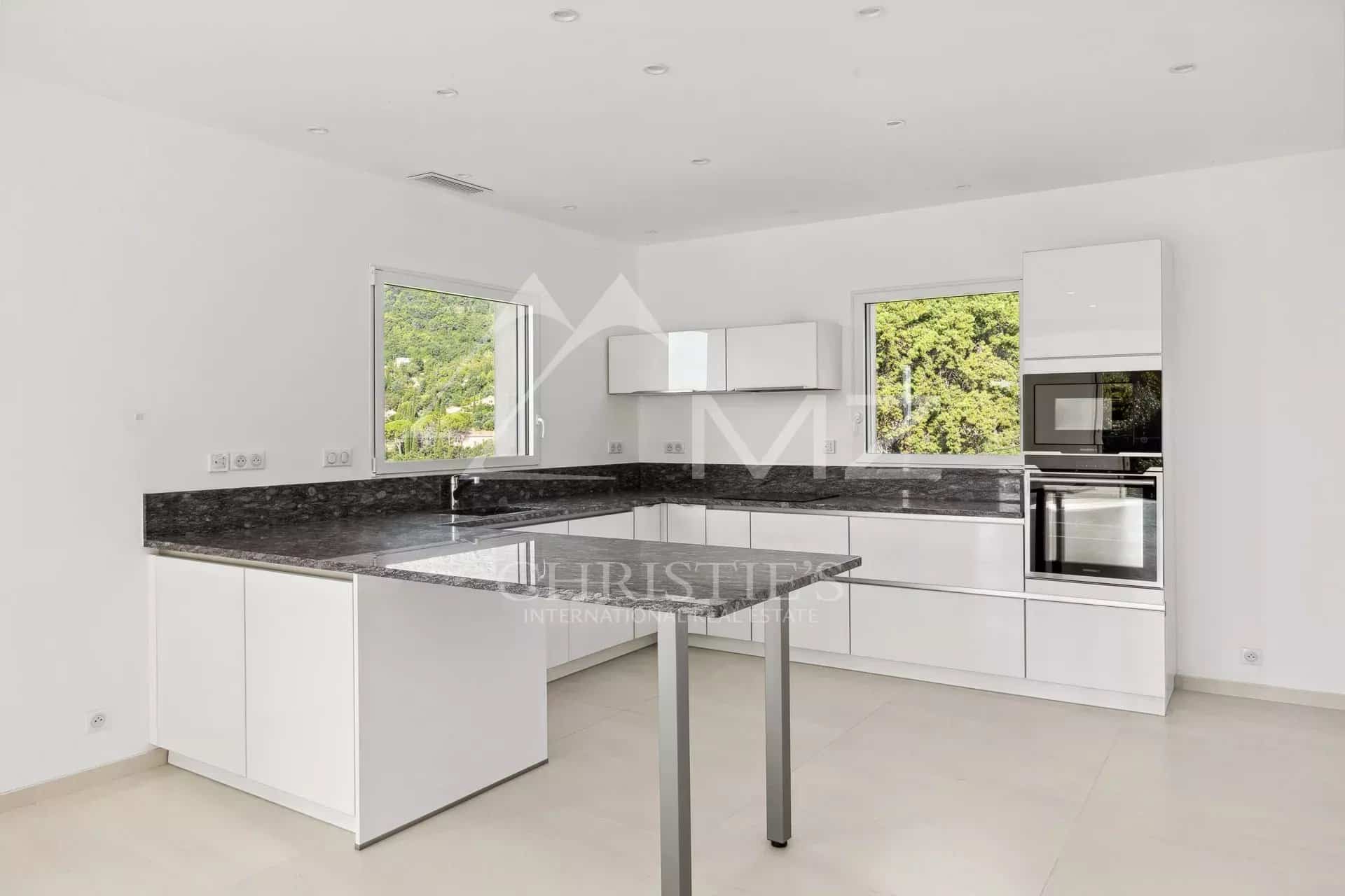 Cuisine moderne et lumineuse d'une villa contemporaine, avec des meubles blancs et un plan de travail en granit.