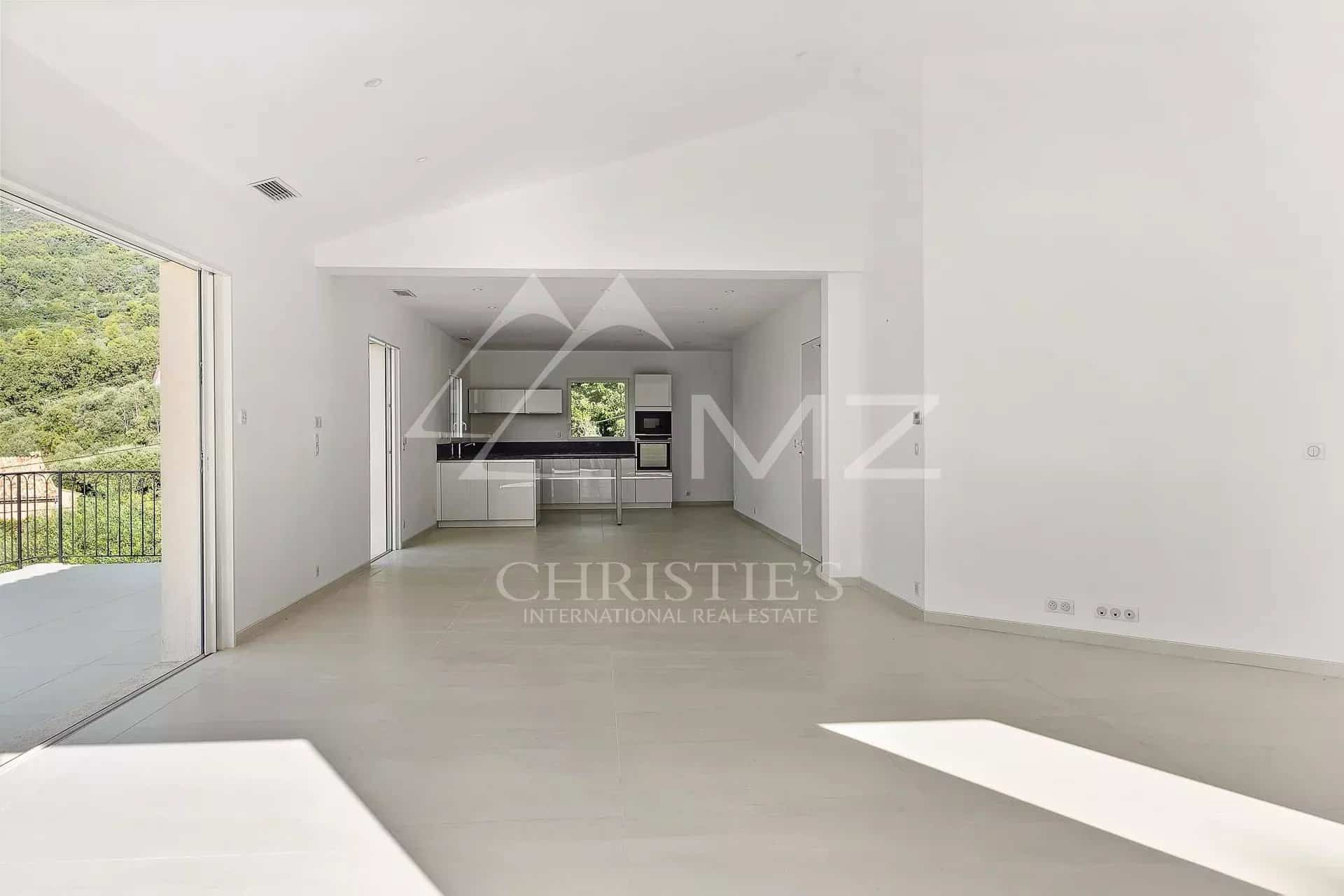 Intérieur d'une villa contemporaine lumineuse avec salon et cuisine ouverte.