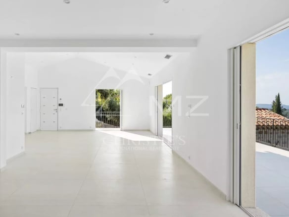 Intérieur d'une villa contemporaine lumineuse avec des grandes baies vitrées et un accès à l'extérieur.