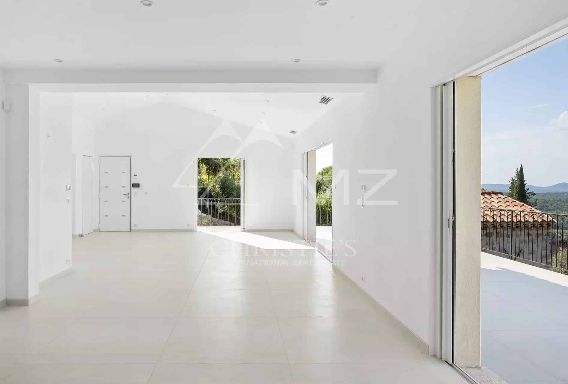 Intérieur d'une villa contemporaine lumineuse avec des grandes baies vitrées et un accès à l'extérieur.