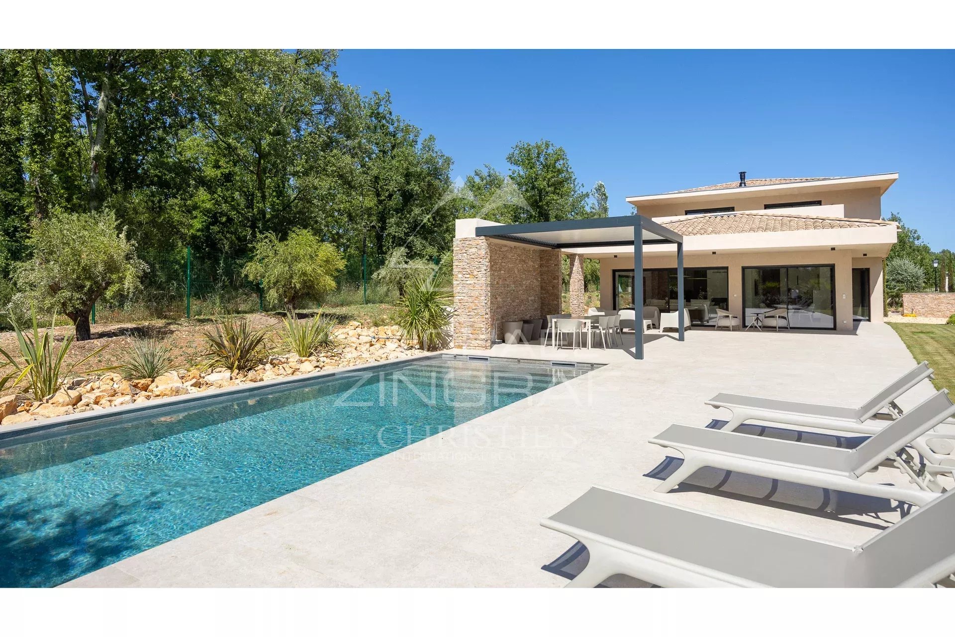 Contemporary villa with swimming pool and terrace in Fayence, surrounded by greenery.