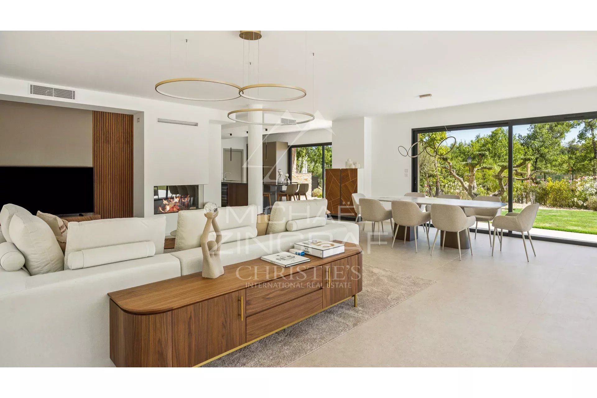 Interior of a contemporary villa with a bright living room, open kitchen and garden view.