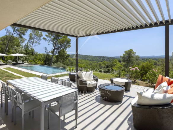 Terrace of a contemporary villa with swimming pool and garden furniture in Roquefort-les-Pins, overlooking the valley.