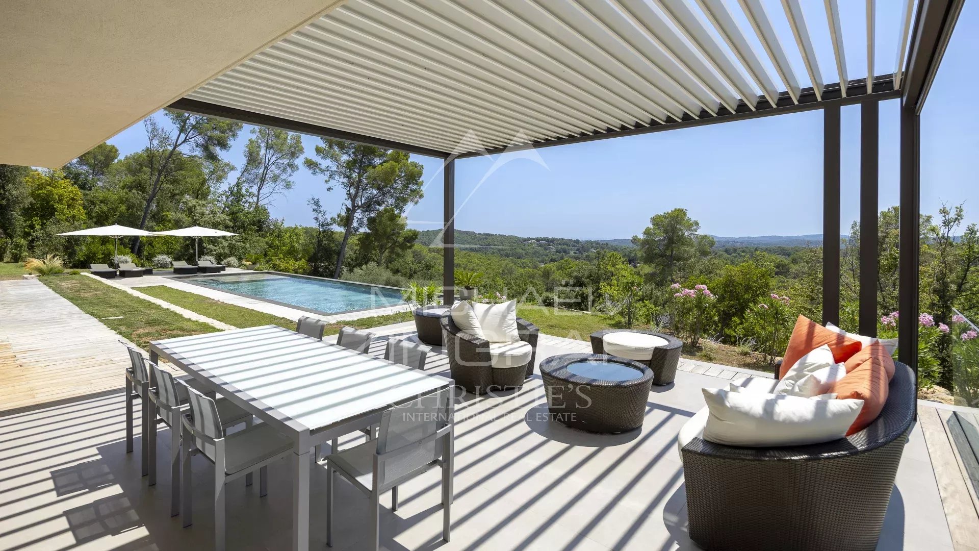 Terrace of a contemporary villa with swimming pool and garden furniture in Roquefort-les-Pins, overlooking the valley.