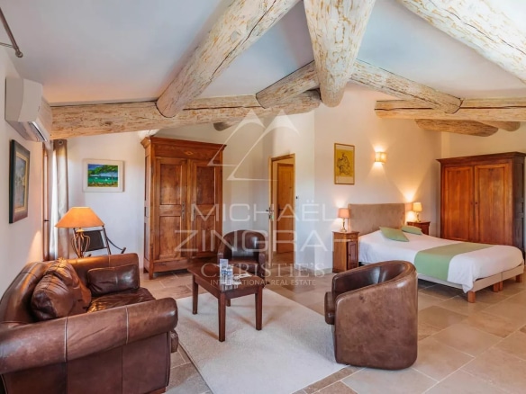 Intérieur d'une chambre spacieuse avec mobilier en bois et plafond à poutres apparentes.