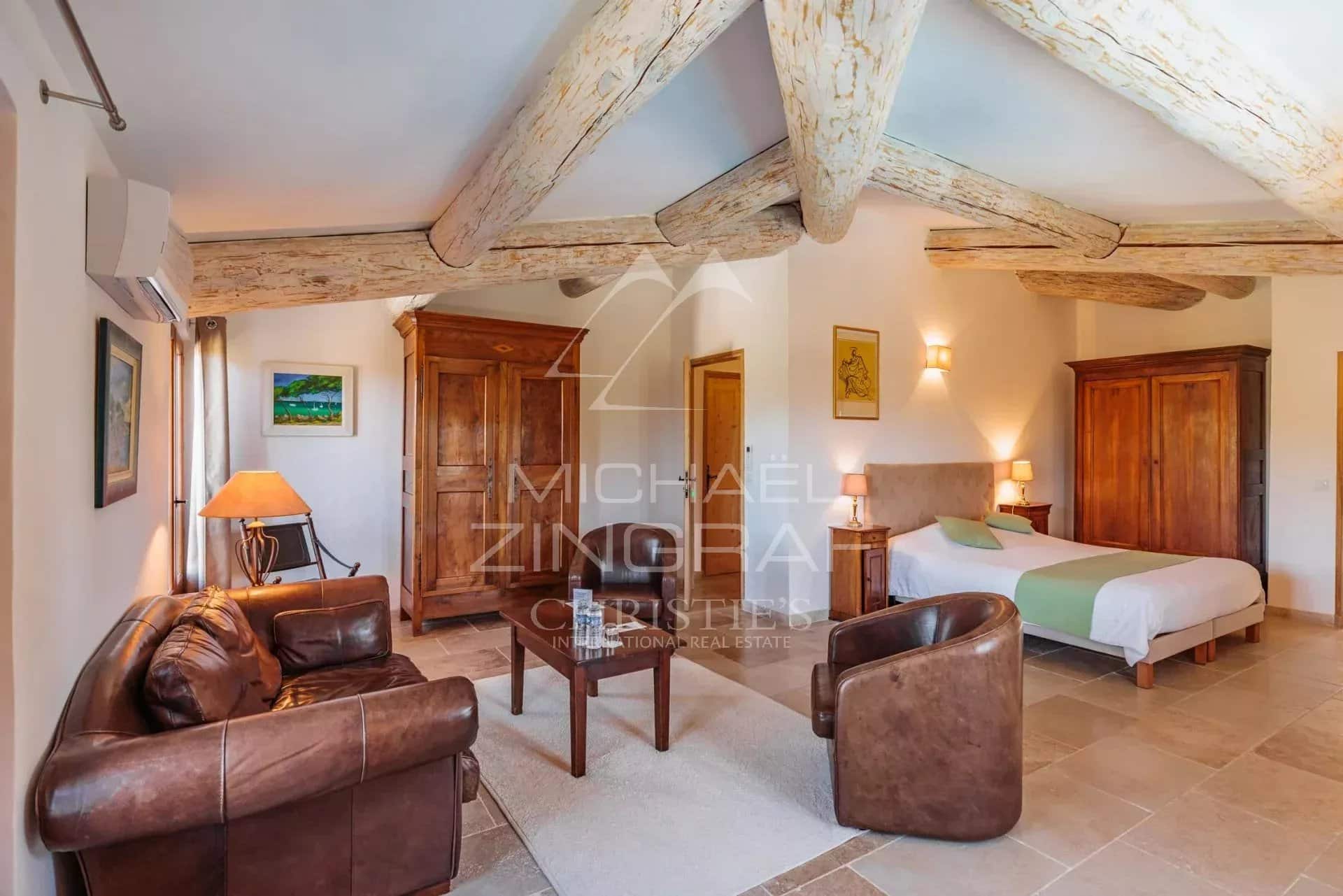 Chambre d’un domaine provençal Intérieur d'une chambre spacieuse avec mobilier en bois et plafond à poutres apparentes.