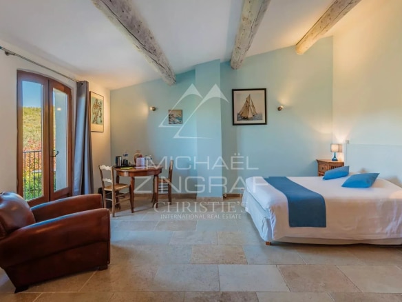 Chambre d'un domaine provençal avec mobilier en bois et vue sur la nature.