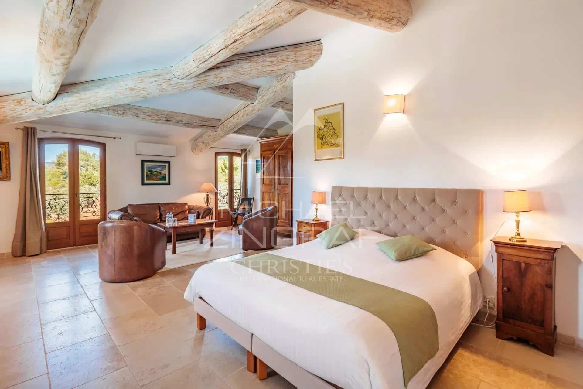 Chambre d’un domaine provençal au Castellet Chambre spacieuse avec lit double, canapés et poutres apparentes dans un domaine provençal.
