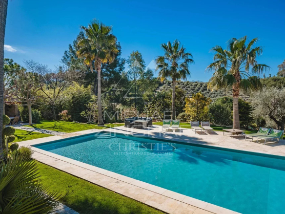 Piscine entourée de palmiers et d'espaces verts dans un domaine provençal