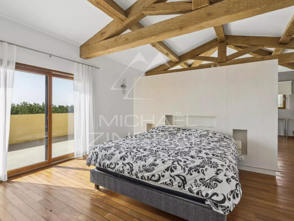 Chambre d'une villa contemporaine avec un lit et des poutres apparentes.