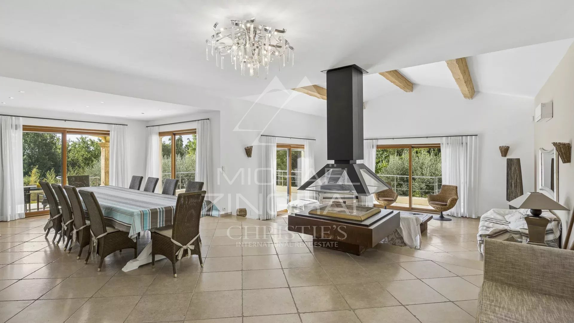 Intérieur d’une villa contemporaine à Fayence Intérieur d'une villa contemporaine avec salle à manger et cheminée, fenêtres donnant sur un jardin.