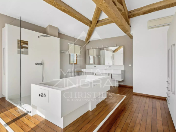 Salle de bain moderne avec baignoire et douche, éclairage naturel, murs clairs et parquet en bois.
