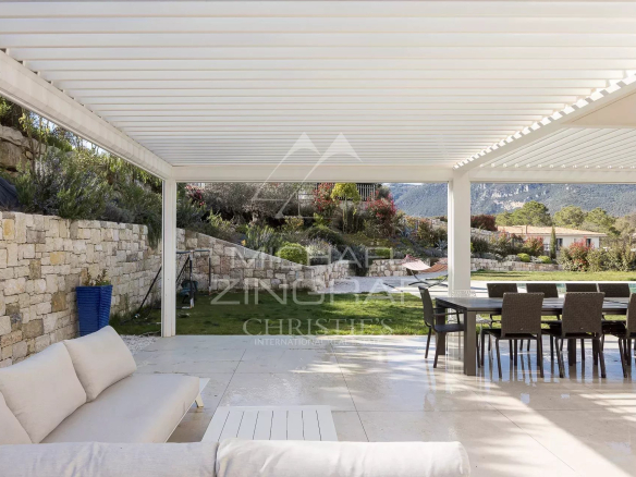 Terrasse d'une villa contemporaine à Roquefort-les-Pins avec mobilier extérieur et vue sur la nature.