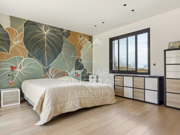 Chambre d'une villa contemporaine à Roquefort-les-Pins avec un mur décoratif et un mobilier moderne.