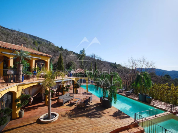 Vue d'une propriété avec piscine et terrasse en bois, entourée de verdure à Bargemon.