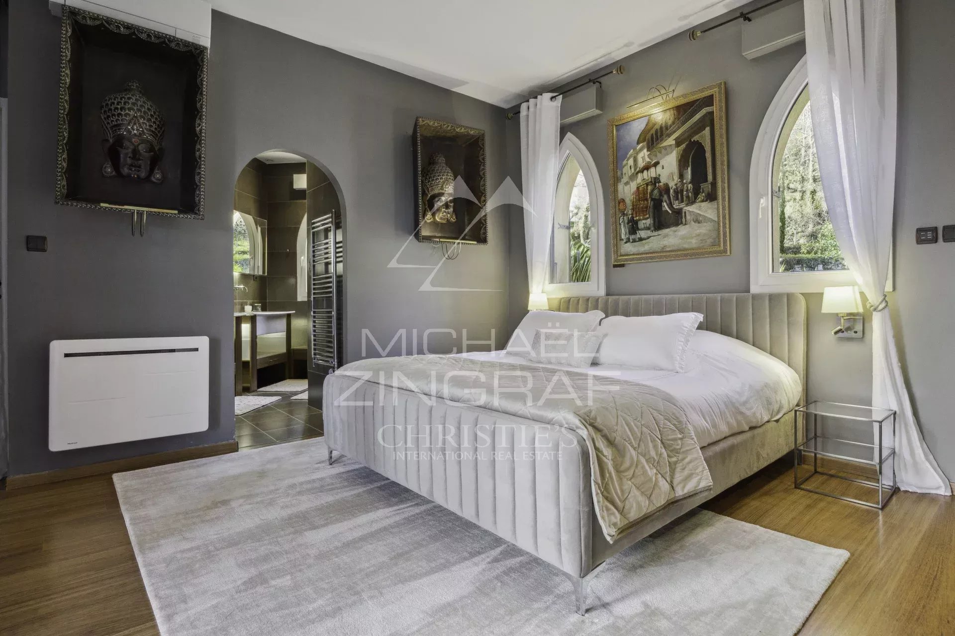 Chambre de propriété à Bargemon Chambre élégante avec lit double et décoration artistique, murs gris, fenêtres en arc.