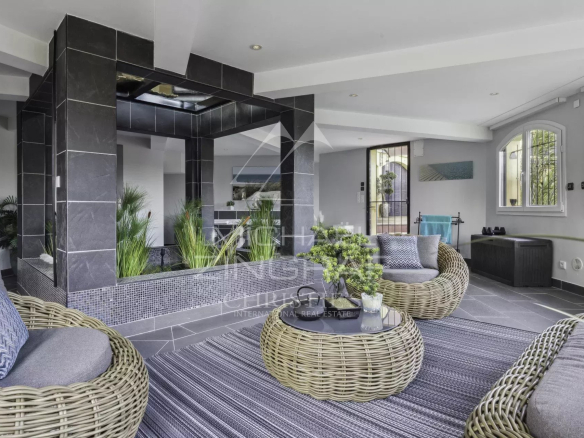 Intérieur d'une propriété de luxe avec des sièges en rotin et des plantes, éclairage moderne.