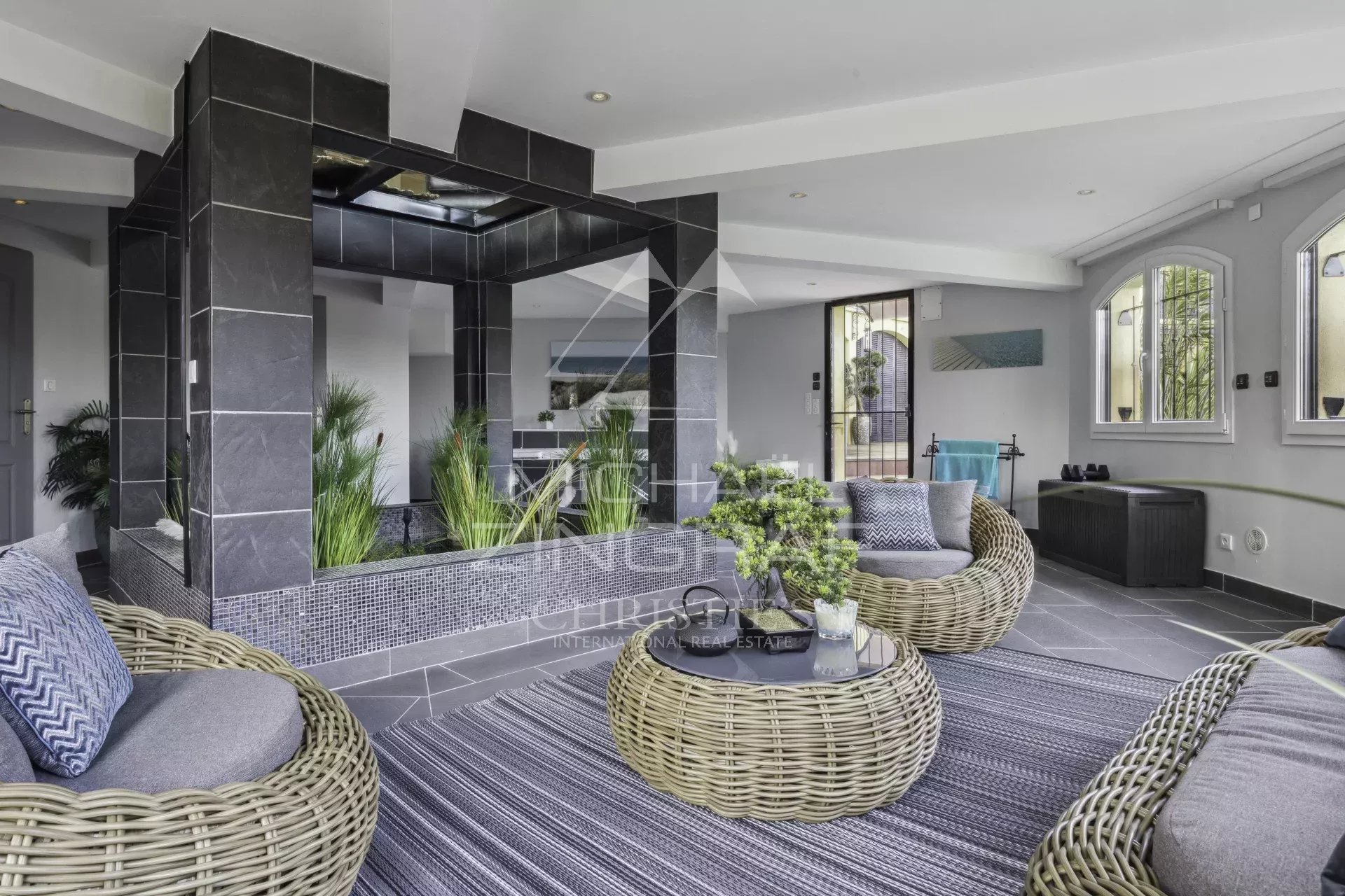 Intérieur d’une propriété de luxe à Bargemon Intérieur d'une propriété de luxe avec des sièges en rotin et des plantes, éclairage moderne.