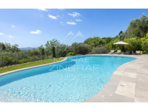 Piscine d'une villa contemporaine avec vue sur les collines et un jardin paysager.