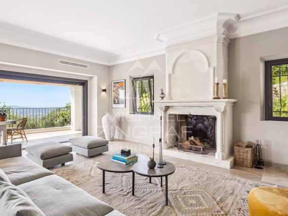 Intérieur d'une villa contemporaine avec cheminée et vue sur les collines.