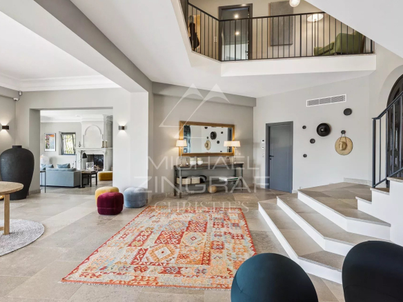 Intérieur d'une villa contemporaine avec un grand hall, un tapis coloré et un escalier moderne.