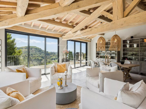 Intérieur d'une villa contemporaine avec vue sur les collines, salon lumineux et mobilier moderne.