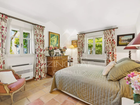 Chambre d'une villa provençale avec décoration chaleureuse et fenêtres donnant sur un jardin.